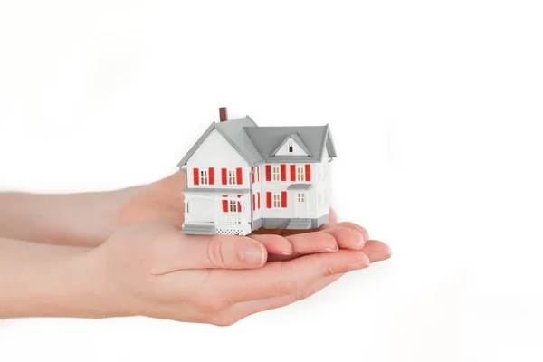 Handen met een miniatuur huis op een witte achtergrond — Stockfoto