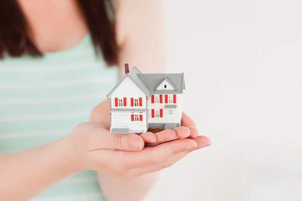 Mujer sosteniendo una casa en miniatura mientras está de pie — Foto de Stock