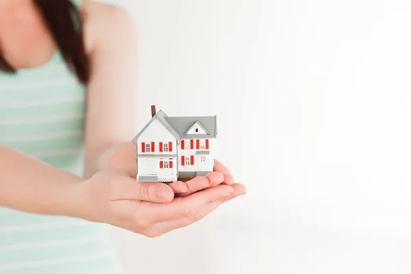 Mujer sosteniendo una casa en miniatura mientras está de pie — Foto de Stock