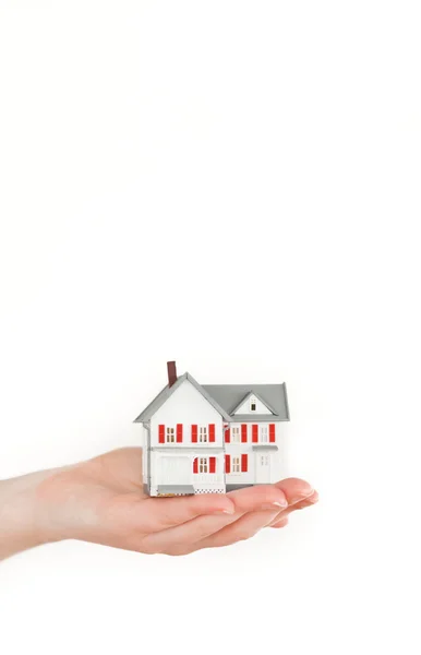 Mano sosteniendo una casa en miniatura sobre un fondo blanco — Foto de Stock