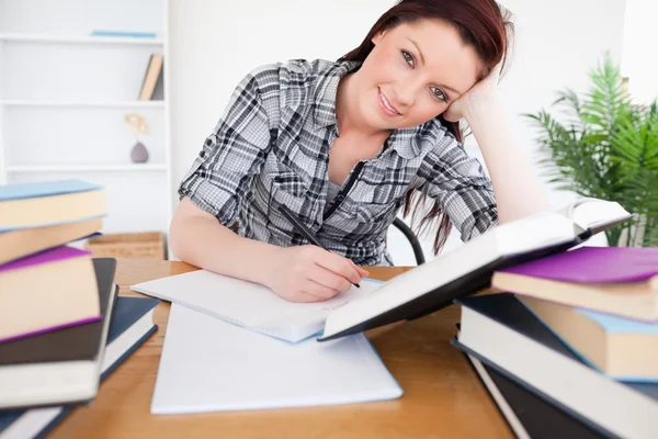 Mujer pelirroja de buen aspecto estudiando en su escritorio —  Fotos de Stock