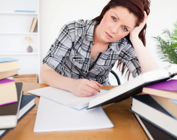 Mujer deprimida de buen aspecto estudiando en su escritorio — Foto de Stock