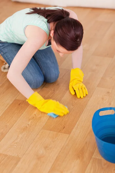 Bra rödhårig kvinna rengöring golvet medan knästående — Stockfoto