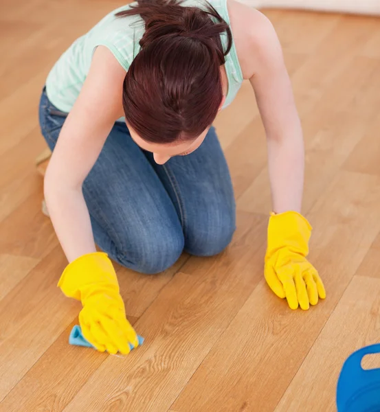 Attraente donna dai capelli rossi che pulisce il pavimento inginocchiandosi — Foto Stock