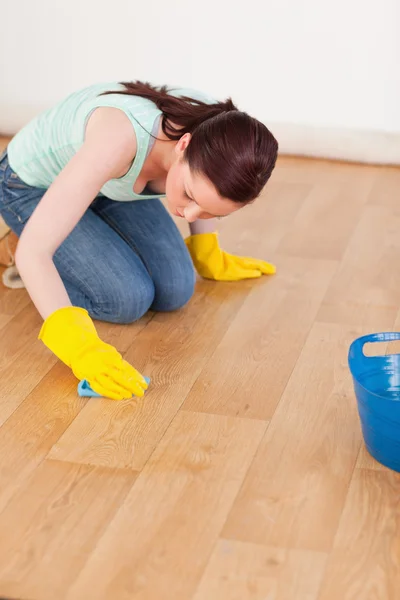Hübsche rothaarige Frau putzt den Boden, während sie kniet — Stockfoto
