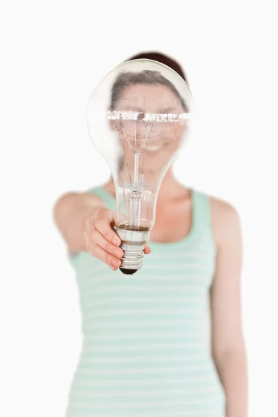 Pretty red-haired female holding a light bulb house while standi — Stock Photo, Image