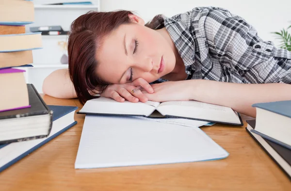 Bastante pelirroja chica descansando mientras estudia en su escritorio —  Fotos de Stock