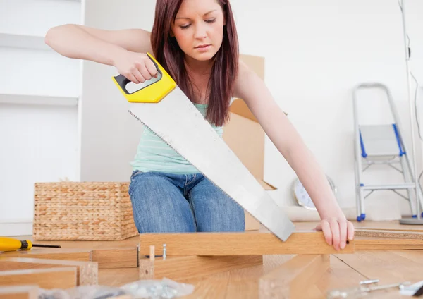 Beautiful red-haired female using a saw for diy at home — Stock Photo, Image