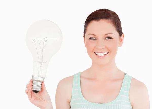 立っている電球を保持している魅力的な赤い髪の女性 — ストック写真
