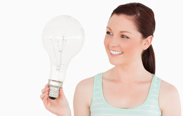 立っている電球を保持している魅力的な赤い髪の女性 — ストック写真
