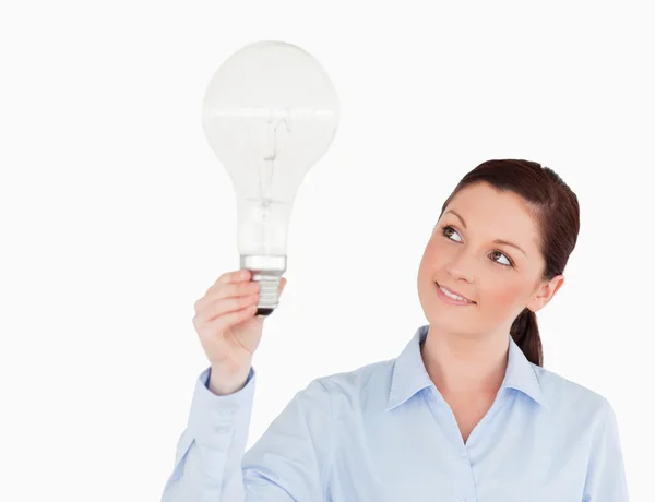 Gorgeous red-haired woman holding a light bulb while standing — Stock Photo, Image