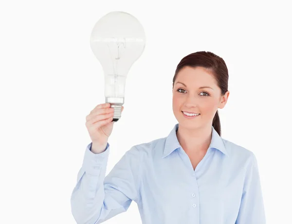 Attractive red-haired woman holding a bulb while standing — Stock Photo, Image