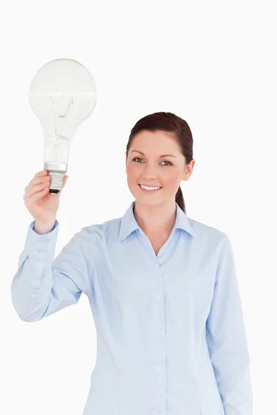 Good looking red-haired female holding a bulb while standing — Stock Photo, Image