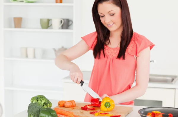 Чудова рудоволоса жінка, що ріже моркву на кухні — стокове фото