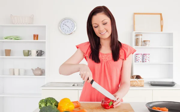 Splendida donna dai capelli rossi che taglia alcune verdure in cucina — Foto Stock