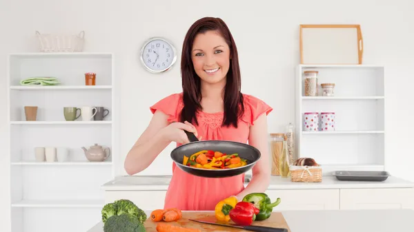 Hermosa mujer pelirroja cocinando verduras en la cocina — Foto de Stock