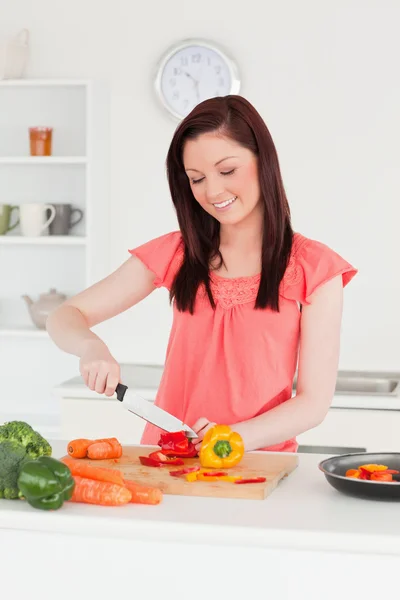 Young attractive red-haired woman cutting some carrots in the ki — Stock Photo, Image