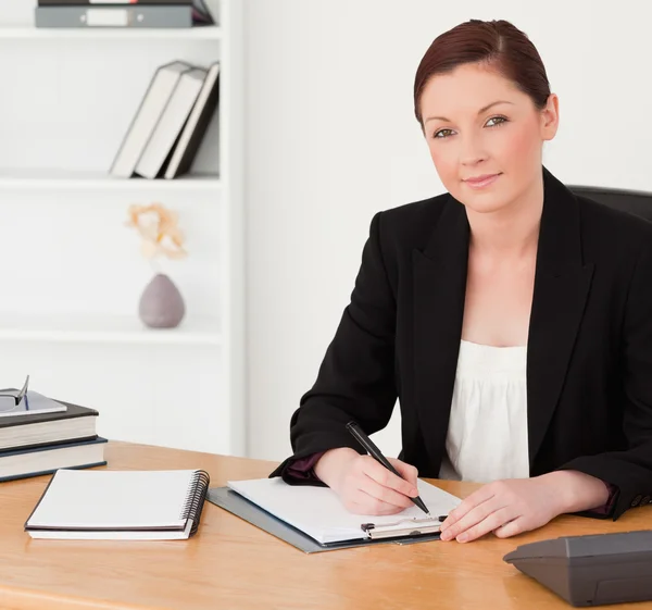 Good looking red-haired woman in suit writing on a notepad — Stock Photo, Image