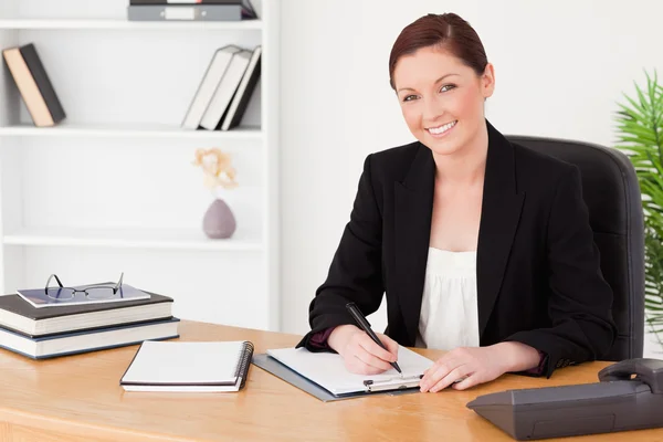 Mujer pelirroja bonita con traje escribiendo en un bloc de notas — Foto de Stock