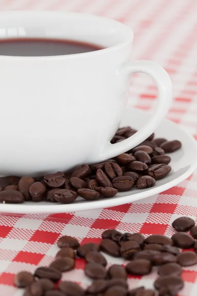Coffee, saucer and beans on a tablecloth — Stock Photo, Image