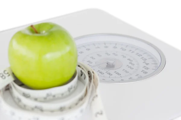 Green apple circled with a tape measure and weigh-scale — Stock Photo, Image