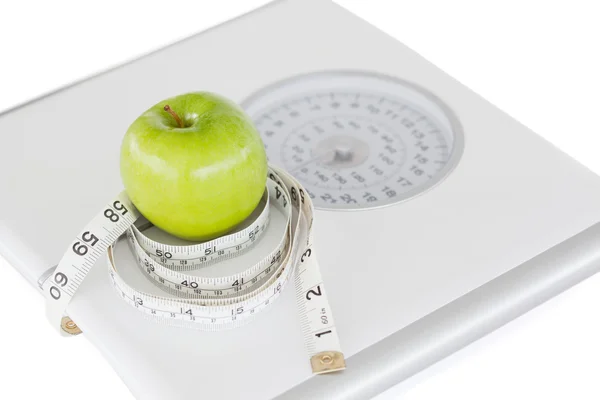 Green apple circled with a tape measure and weigh-scale — Stock Photo, Image
