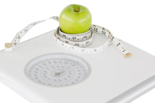 Green apple circled with a tape measure and a weigh-scale — Stock Photo, Image