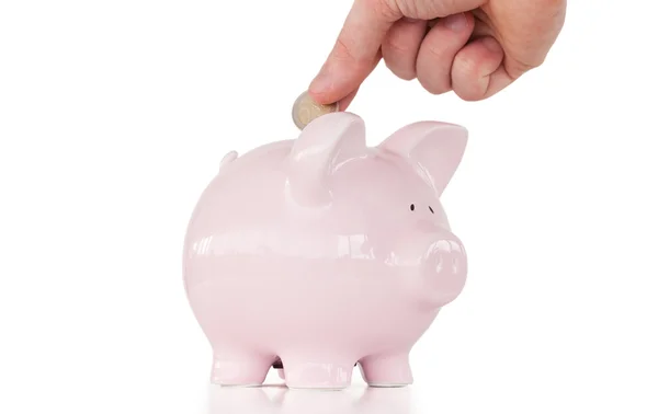 Hand invoegen van een munt in een roze piggy bank — Stockfoto