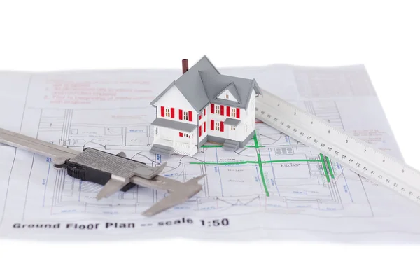 Toy house model and ruler and on a plan against a white backgrou — Stock Photo, Image
