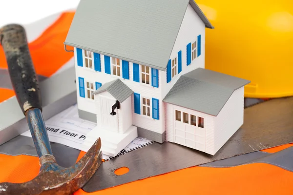 Hulpmiddelen en miniatuur huis op een oranje jas — Stockfoto
