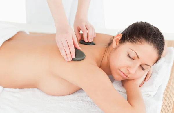 Mulher de cabelos escuros relaxante ao ter uma massagem de pedra — Fotografia de Stock