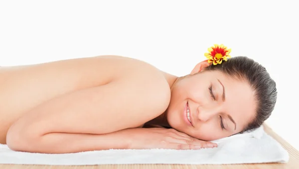 Young woman lying on a massage table and a flower on her ear — Stock Photo, Image