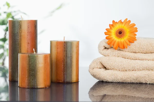 Unbeleuchtete Kerzen mit orangefarbener Gerbera auf Handtüchern — Stockfoto