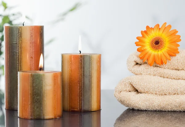 Зажженные свечи с оранжевой герберой на полотенцах — стоковое фото