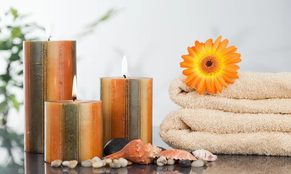 Velas iluminadas com uma gerbera laranja em toalhas e conchas do mar — Fotografia de Stock