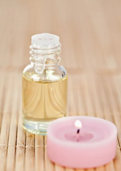 Pink lighted candle and glass phial — Stock Photo, Image