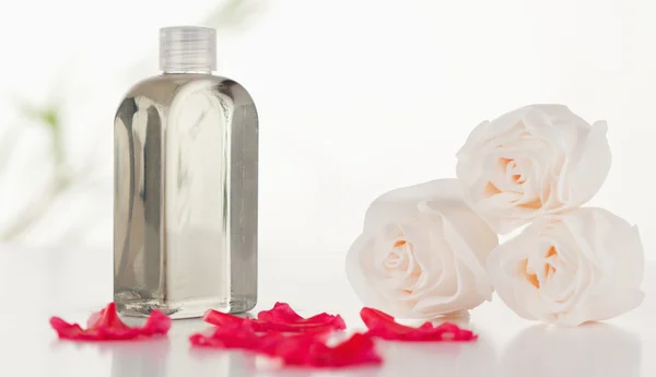 Glass flask with petals and roses — Stock Photo, Image