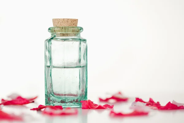 Pétalas cor-de-rosa e frasco de vidro — Fotografia de Stock