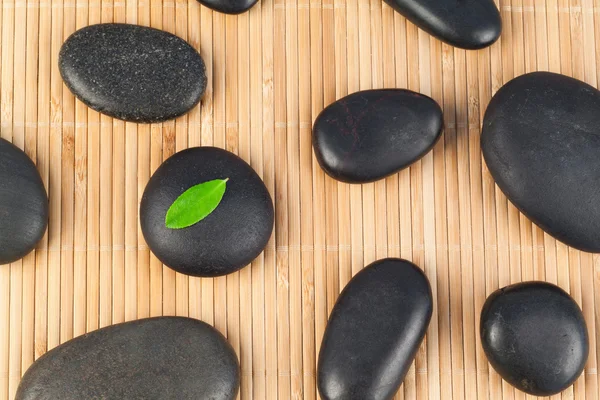 Black stones with a leaf on one of them — Stock Photo, Image