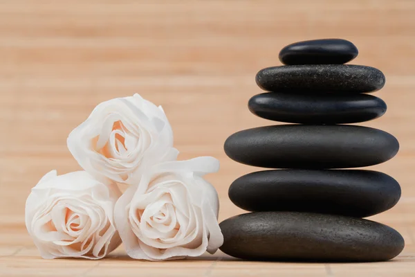 Nahaufnahme von Rosen und einem Stapel schwarzer Kieselsteine — Stockfoto