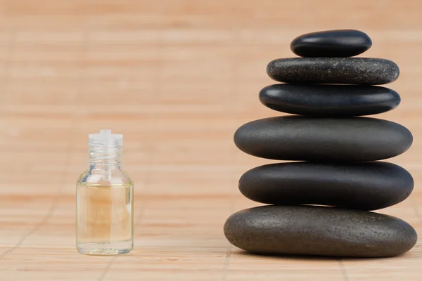 Close up of a glass phial and a black pebbles stack — Stock Photo, Image