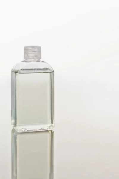 Glass flask on a mirror against white background — Stock Photo, Image
