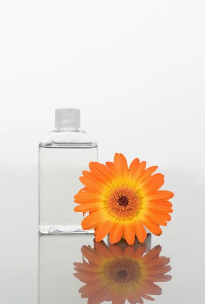 Turuncu gerbera ve bir cam şişeye bir ayna üzerinde — Stok fotoğraf