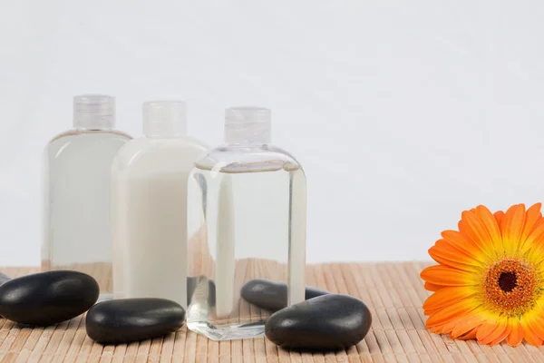 Slunečnice s černými kameny a láhve masážní oleje — Stock fotografie