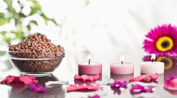 Angezündete rosa Kerzen mit Blütenblättern und einer Schale Kies — Stockfoto