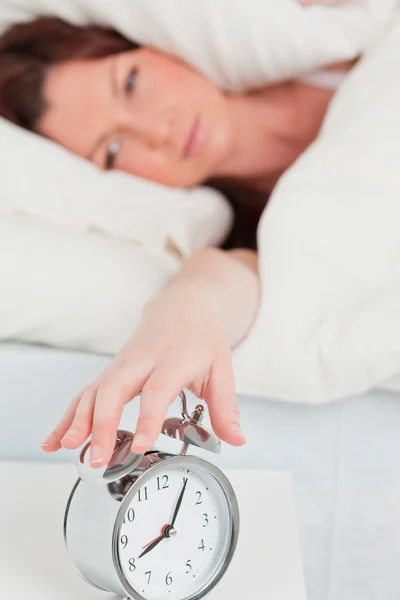 Good looking red-haired woman waking up thanks to an alarm clock — Stock Photo, Image