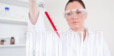 Beautiful red-haired scientist filling up a test tube clipart