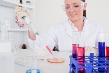 Pretty red-haired scientist using a pipette clipart