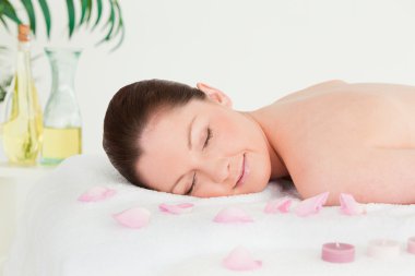 Beautiful woman lying on a massage table with petals and unlight clipart