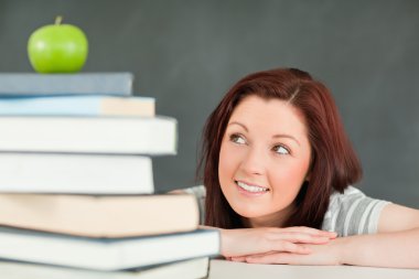 Young student looking at the apple on the top of her books clipart